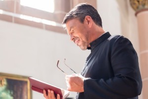 46811577 - catholic priest reading bible in church