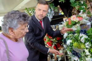 49309639 - undertaker helping woman choose flowers